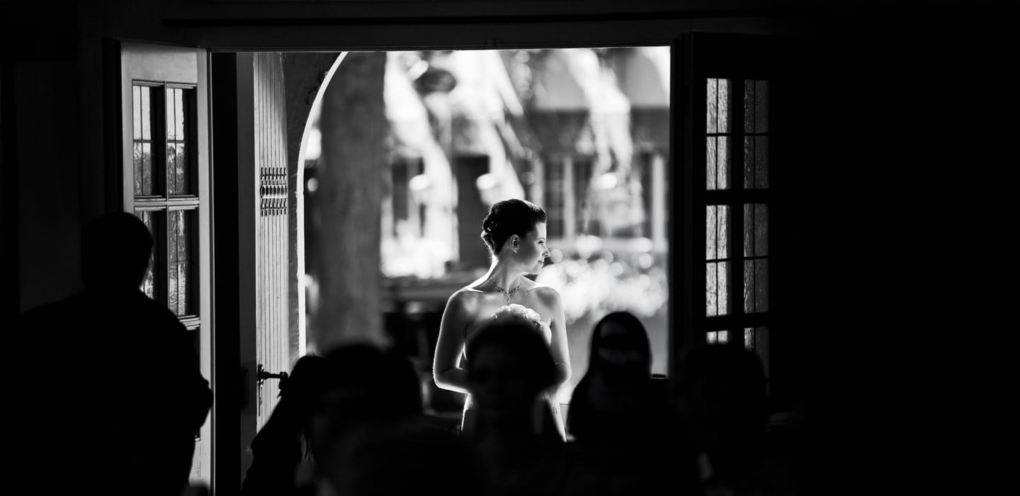 Bride standing in the doorway in the sunlight.