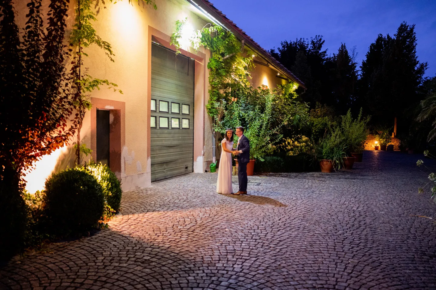 Couple dancing in front of lighted building in the evening.