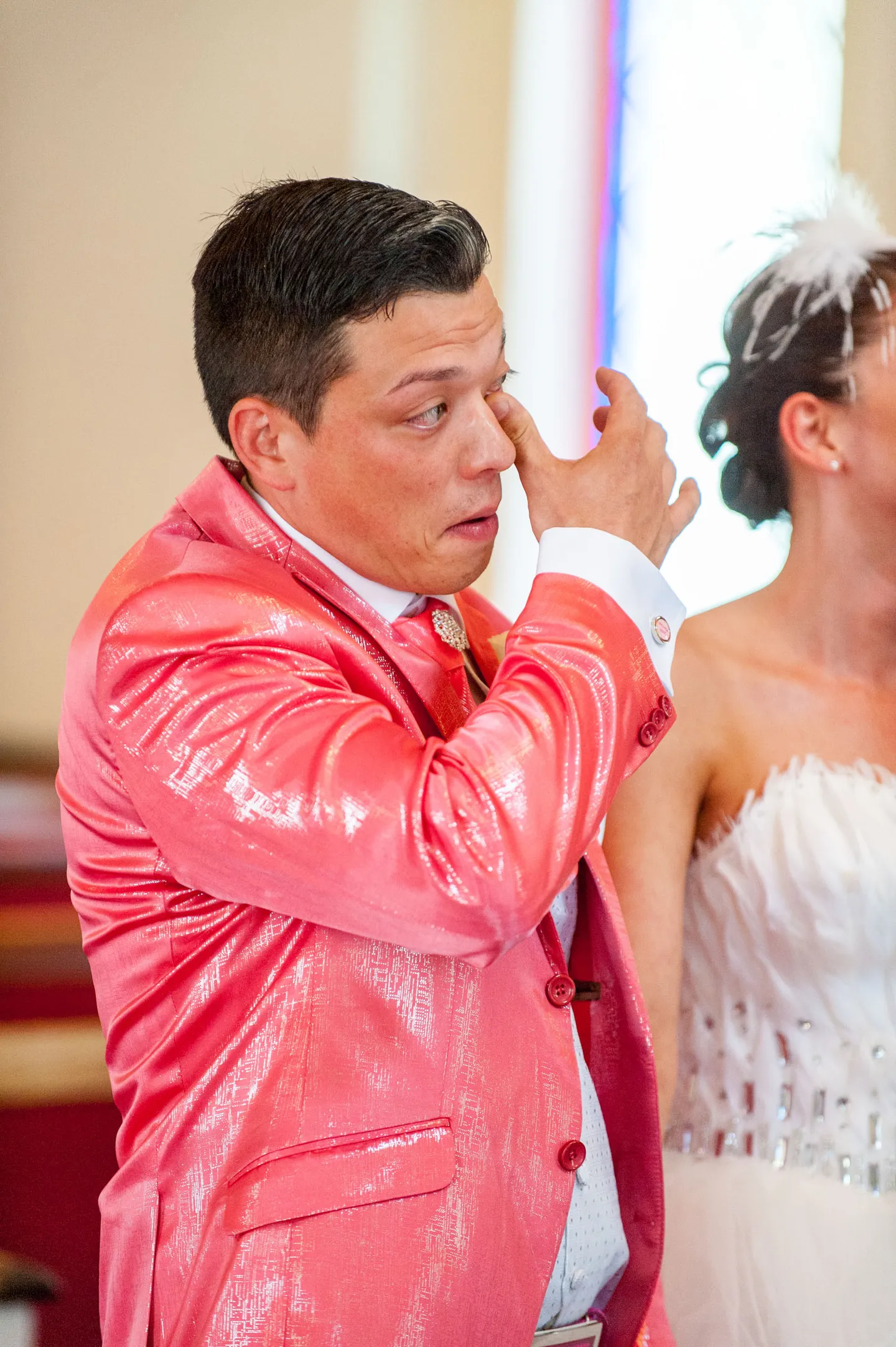 Groom in pink suit emotional during wedding