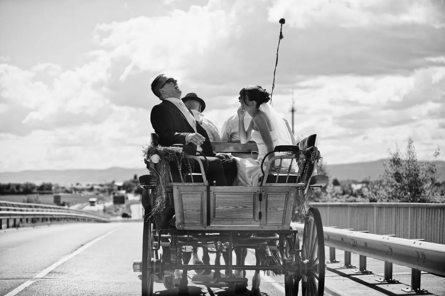 Bridal couple laughing on a horse-drawn carriage