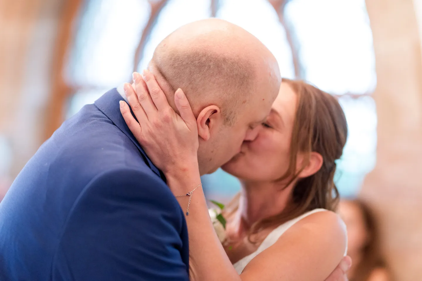 Wedding couple kissing in front of a window.