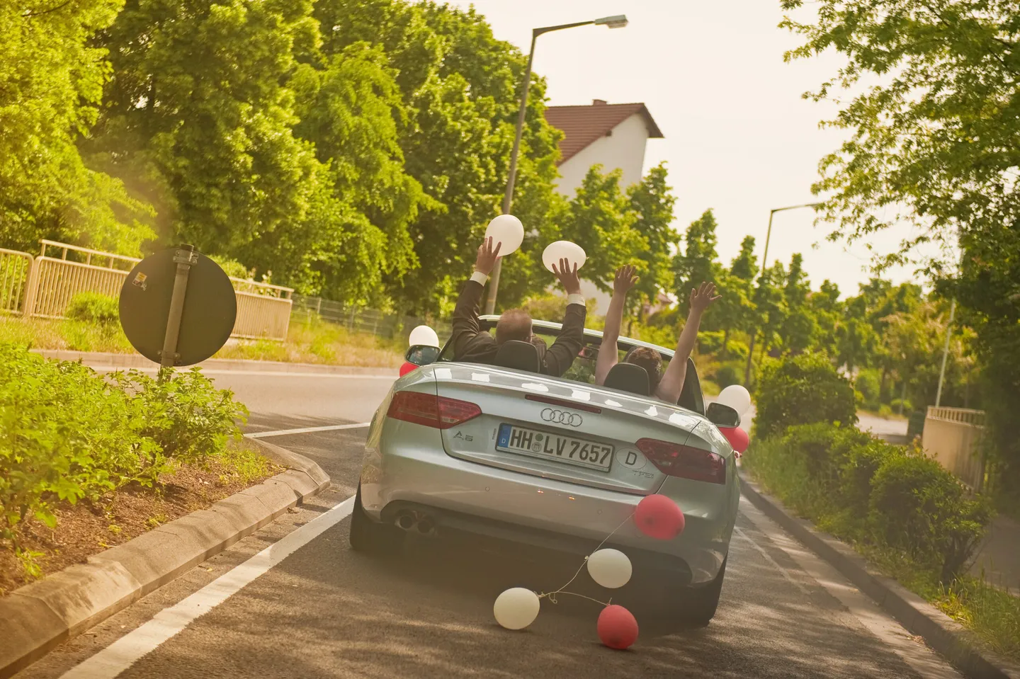 Wedding couples in a convertible with balloons