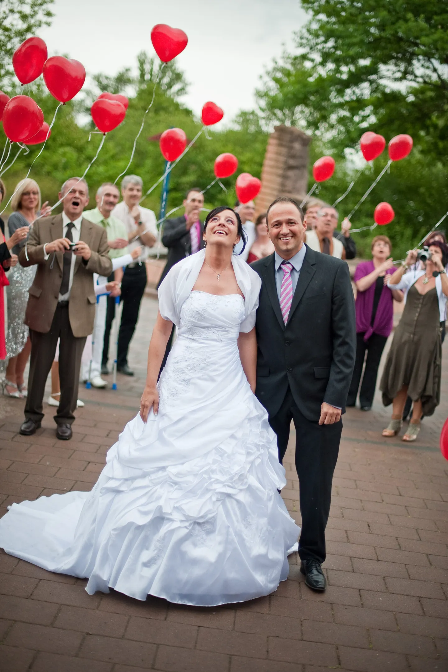 Wedding couple with red balloons and guests