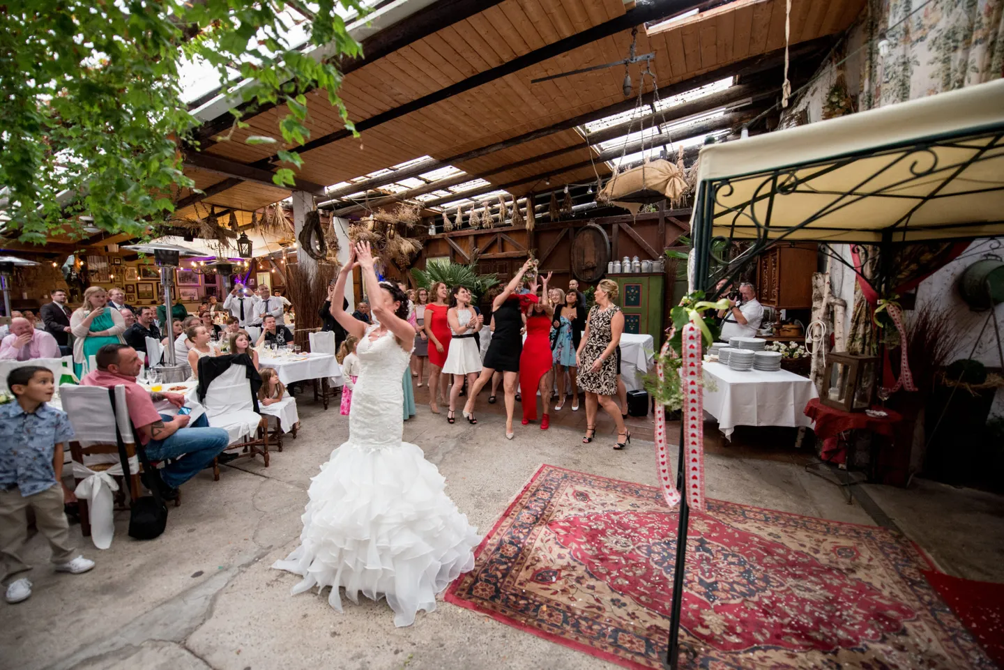 Bride throws bouquet, guests cheer.
