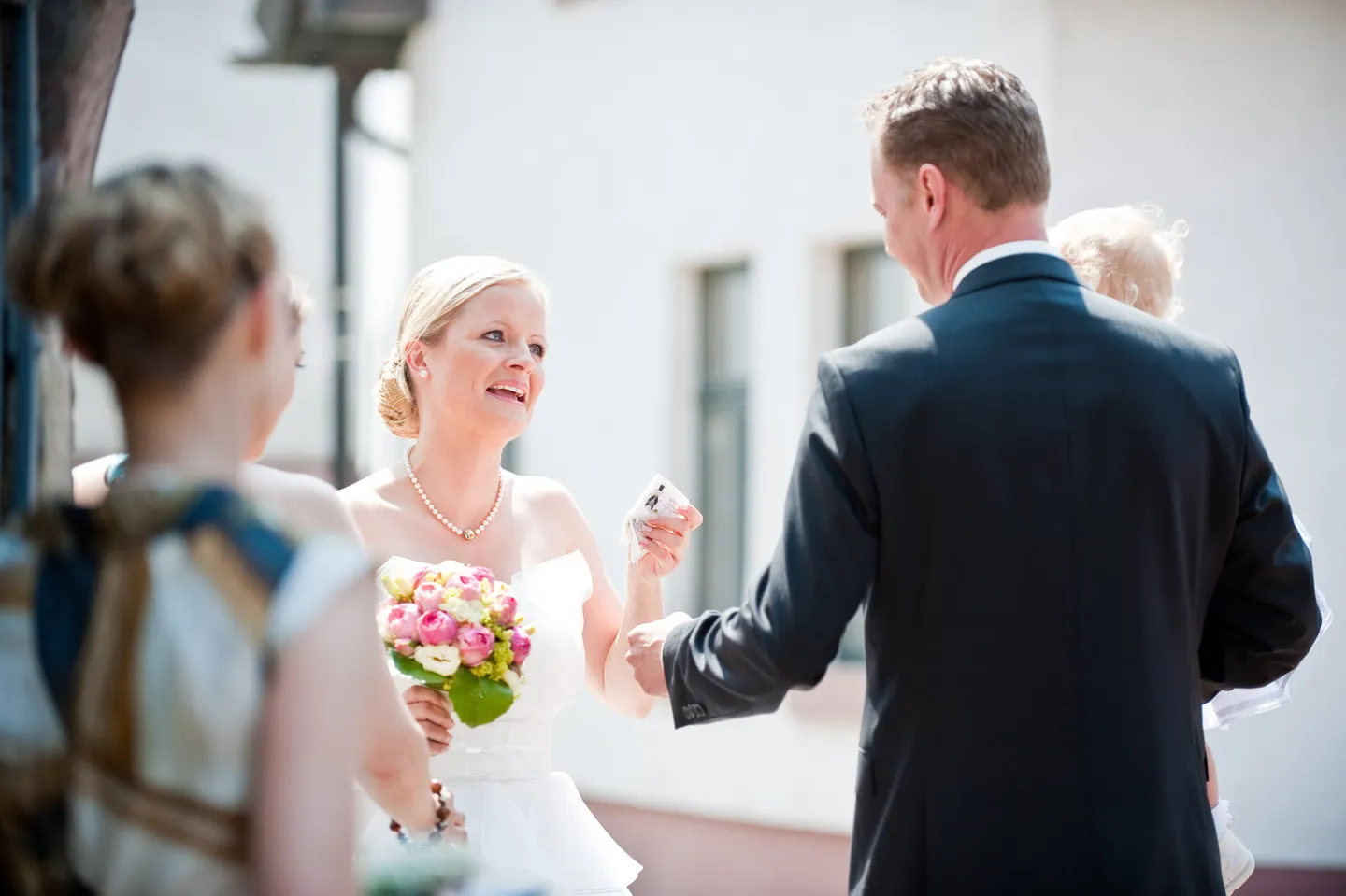 Smiling bride with bouquet and guests