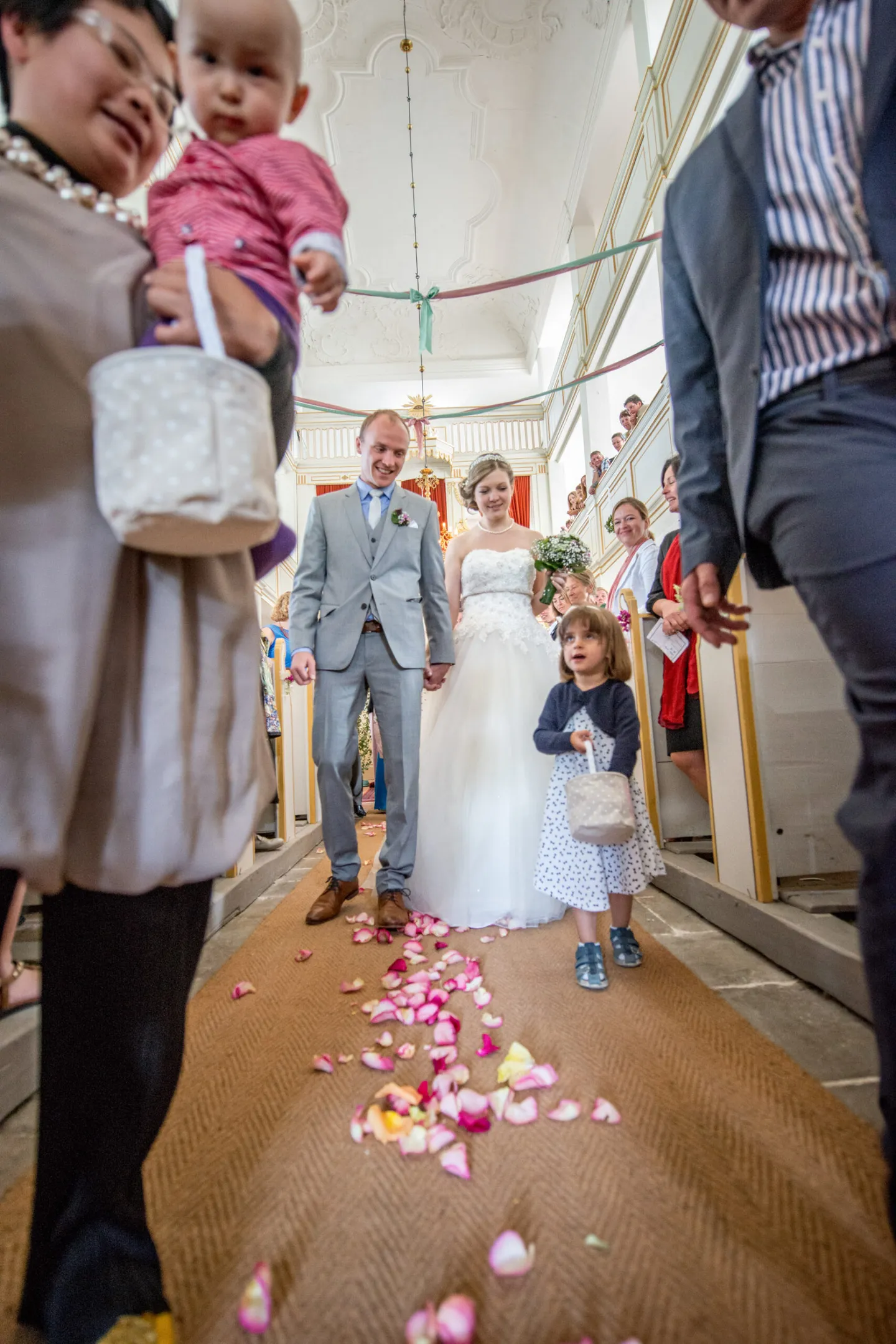 Bride and groom walk over petals in the church.