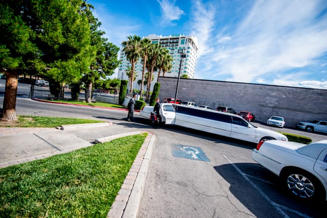 Limousine in front of parking lot, people get in.
