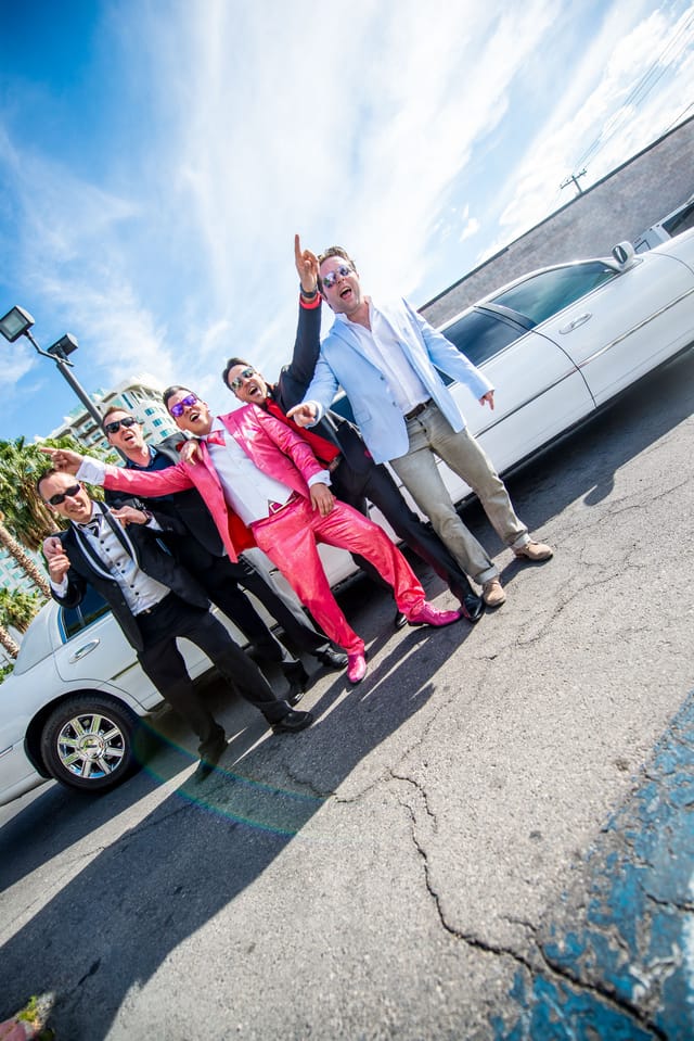 Group of men celebrating in front of a white limousine
