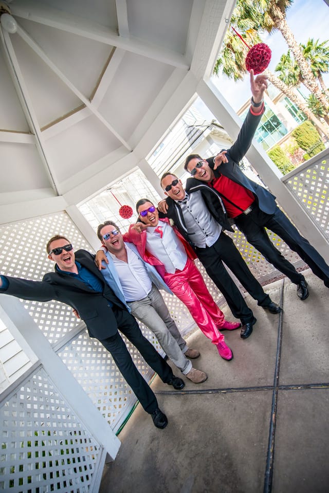 Five men in suits laugh and pose together.
