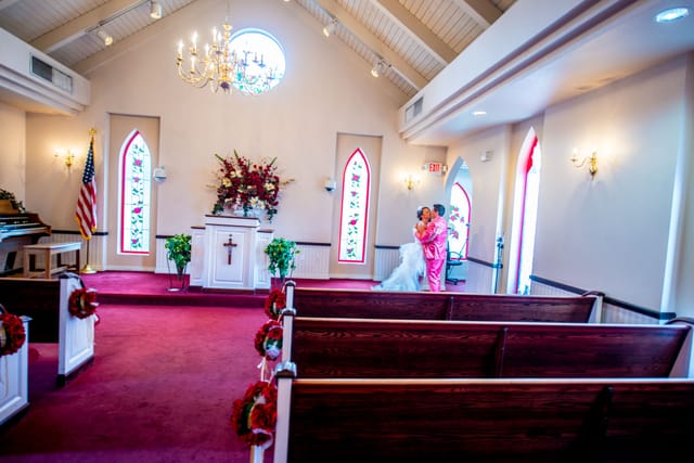 Wedding couple in a chapel with red windows.