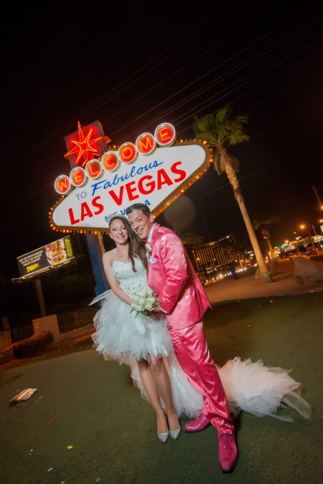 Bride and groom in front of Las Vegas sign at night