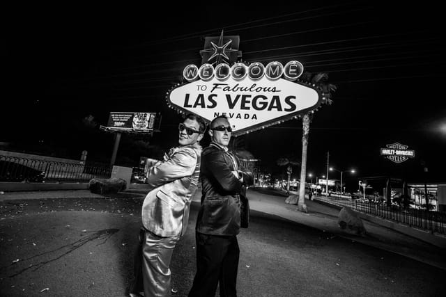 Two men in suits in front of Las Vegas sign