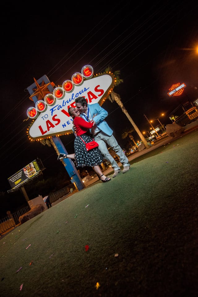 Couple in front of Las Vegas sign at night.