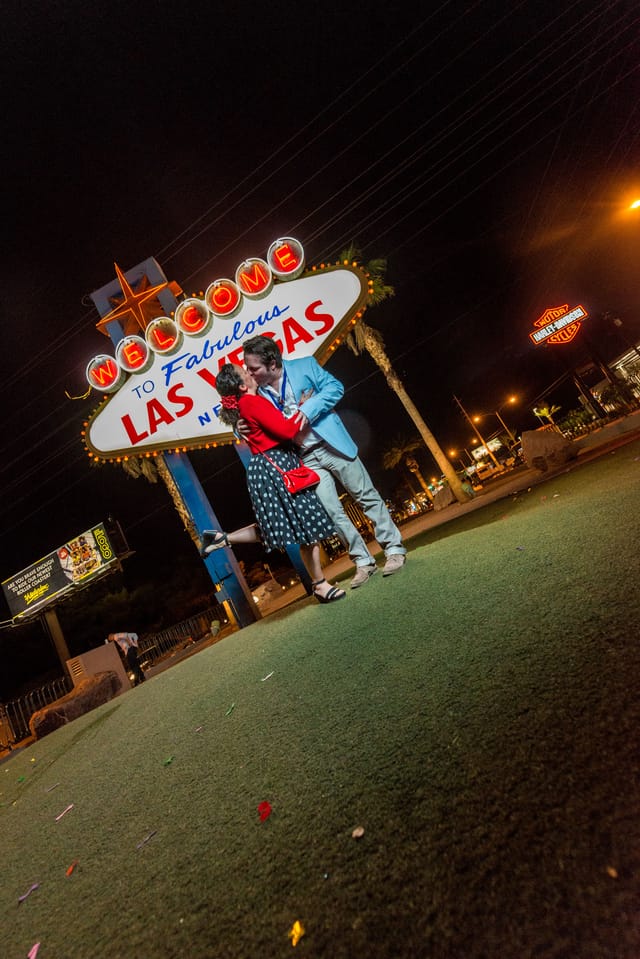Couple kissing in front of Las Vegas sign at night