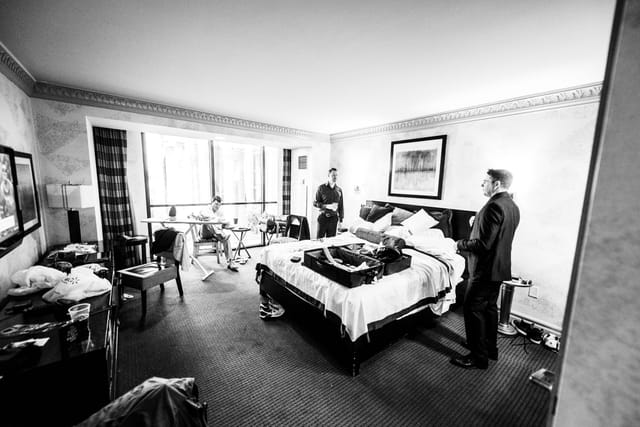Men in suit in hotel room, black and white photo.