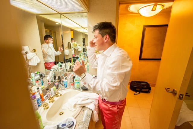 Man applying make-up in front of the bathroom mirror.