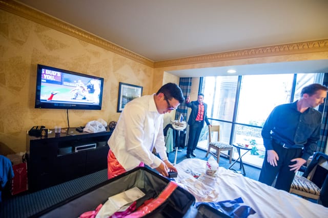 People packing suitcases in a hotel room.