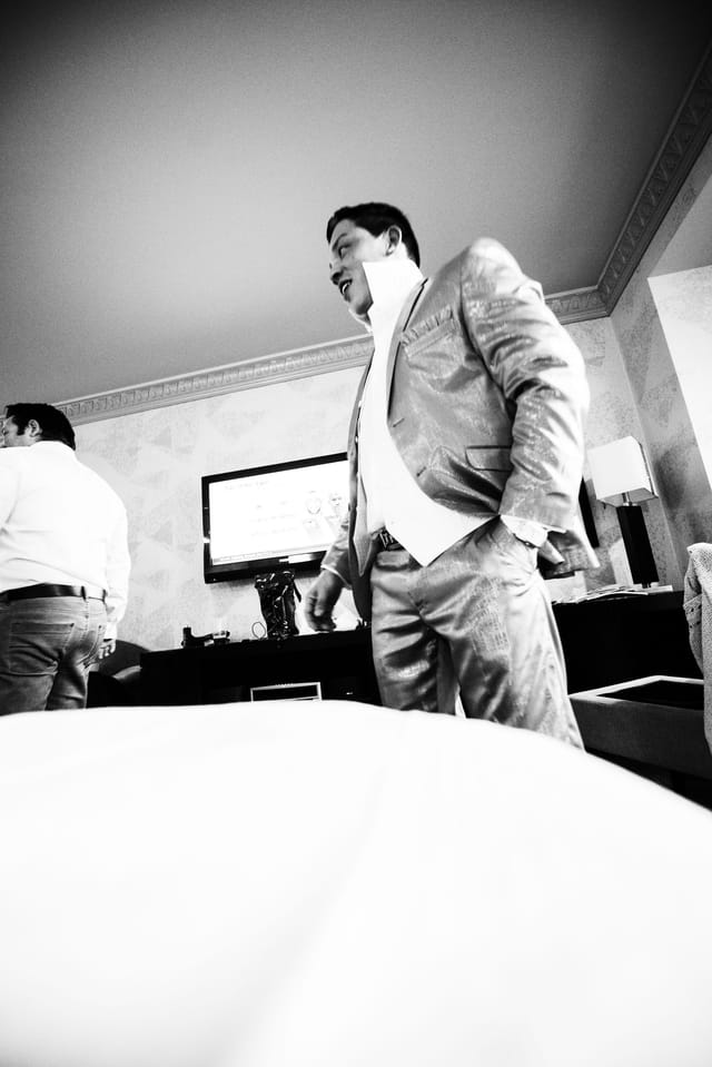 Men in suits in front of the TV in a hotel room