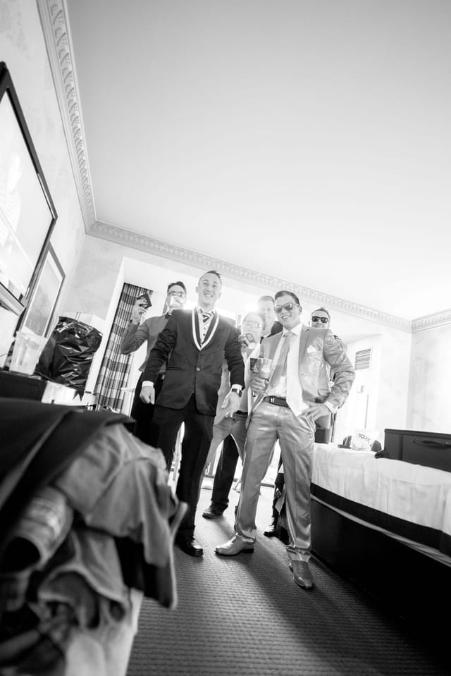 Men in suits celebrate in the hotel room.