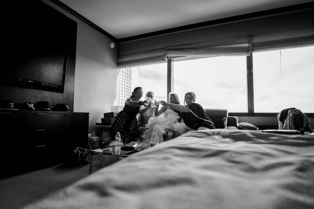 Women in the hotel room clink glasses together.