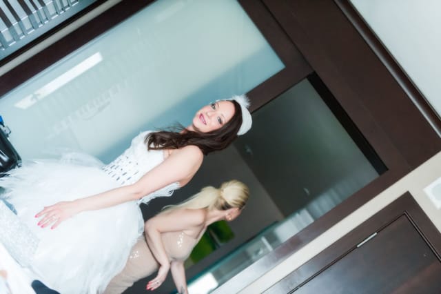 Woman in a white dress in front of a mirror.