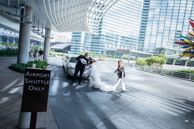 Couple poses in front of limousine against architectural backdrop